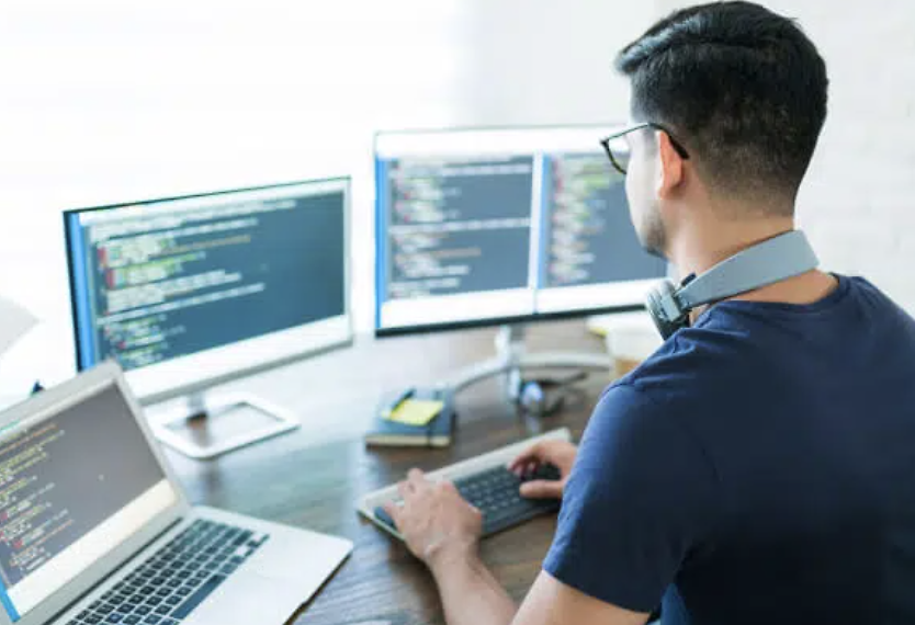 developer coding on four screens
