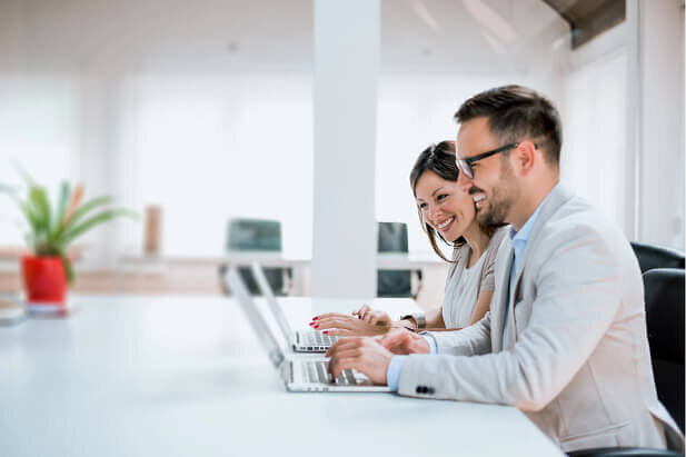 Happy workers using laptops in modern open plan office