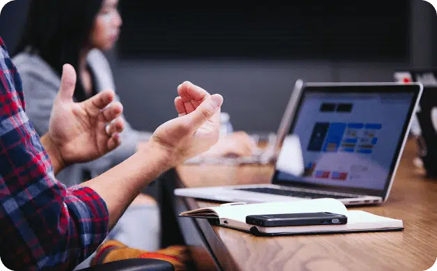 Person gesturing next to laptop