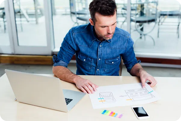 Man looking at a mockup and his laptop