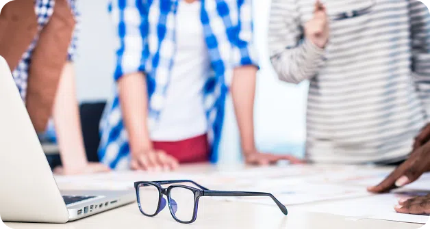 Spectacles on table next to laptop