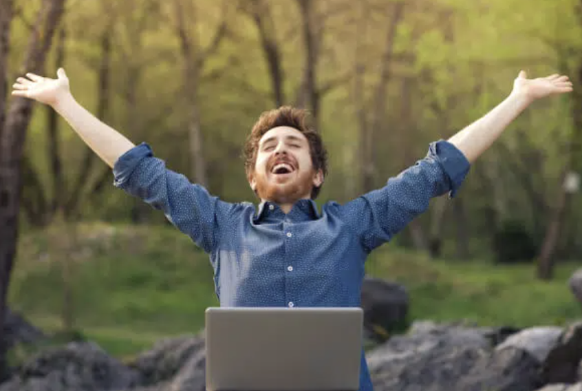 Happy man stretching at laptop outside