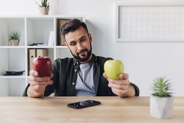 Man at desk holding two apples
