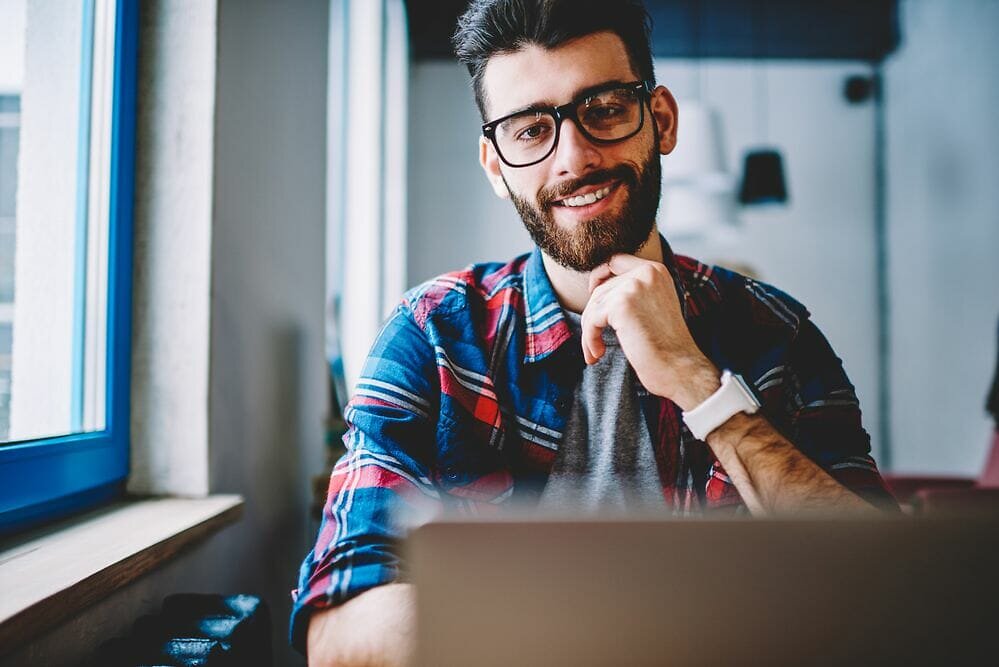 Man With Glasses Smiling In Front Of Laptop